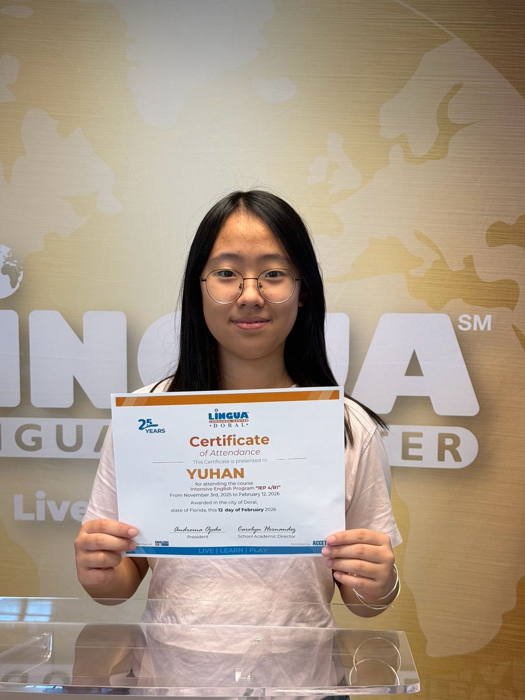 Person holding a certificate in front of a gold branded backdrop
