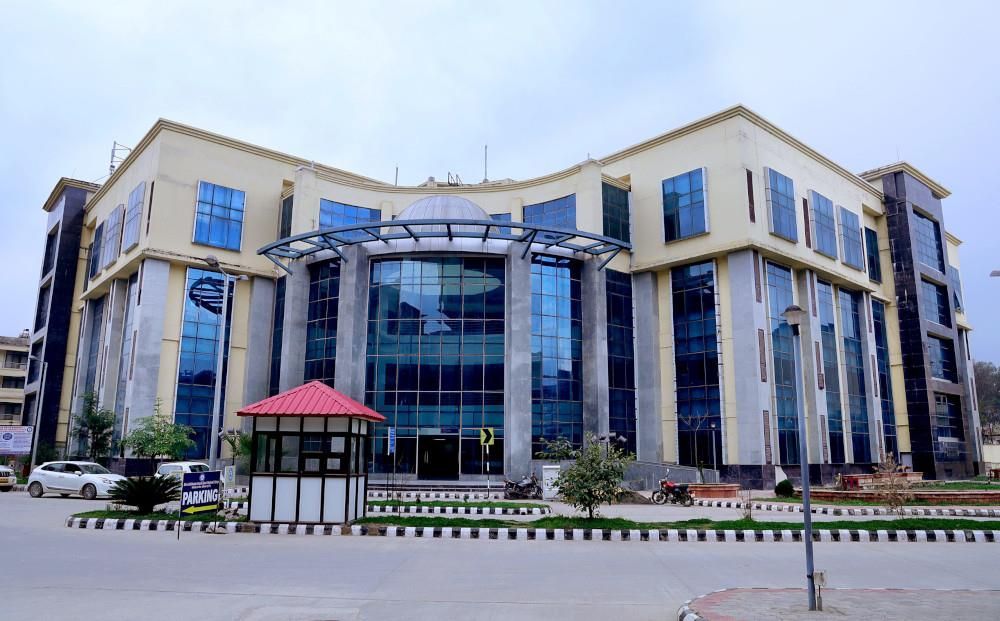 Modern glass-front office building with beige stone фасade and a red-roofed entrance canopy