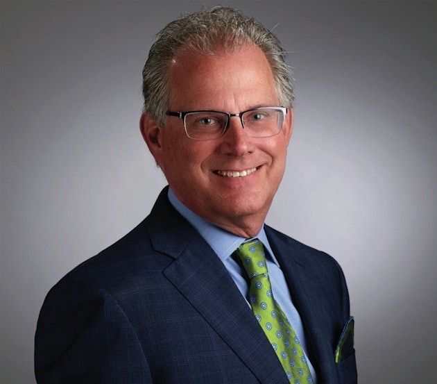 A man in a suit and tie is smiling for the camera