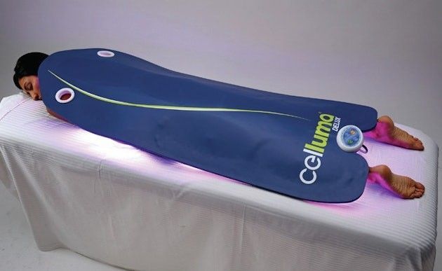 A person is laying on a bed with a celluma blanket on them.