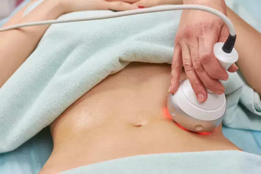 A woman is getting a cavitation treatment on her stomach.