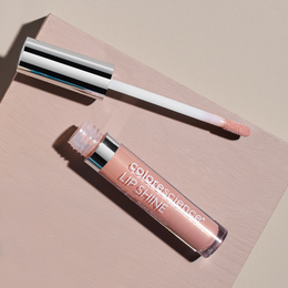 A bottle of color science lip shine on a pink surface