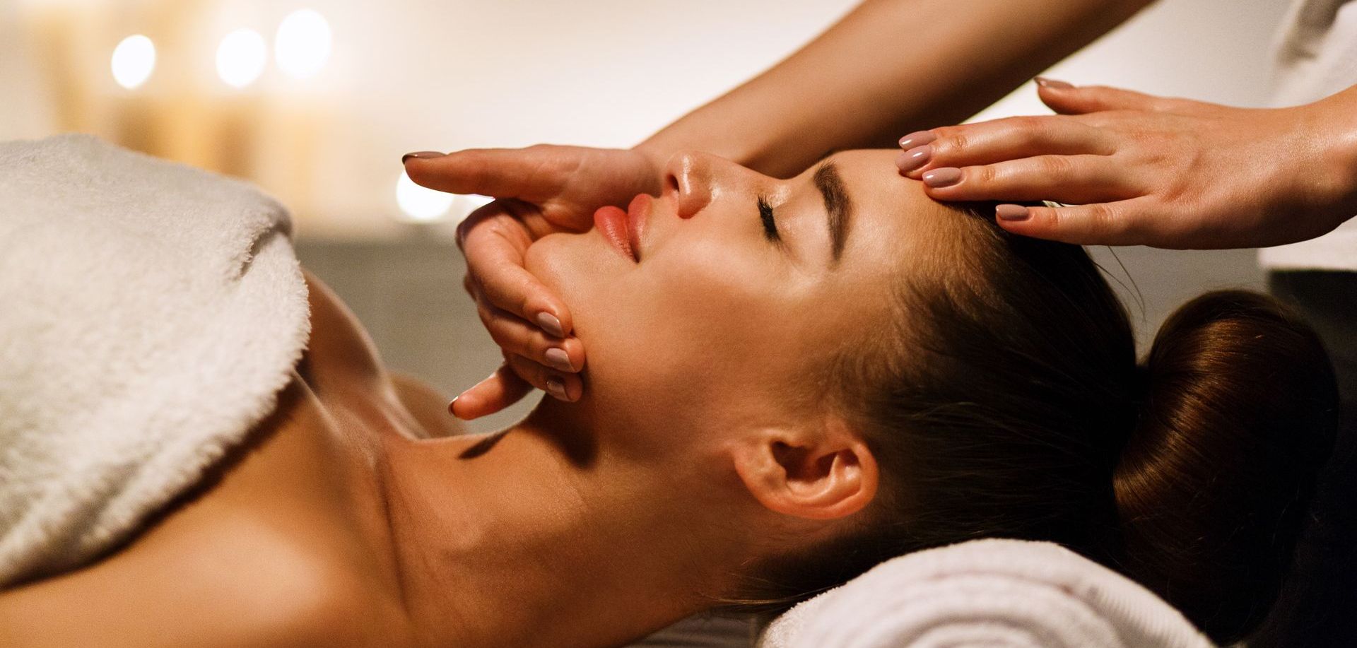 A woman is getting a facial massage at a spa.