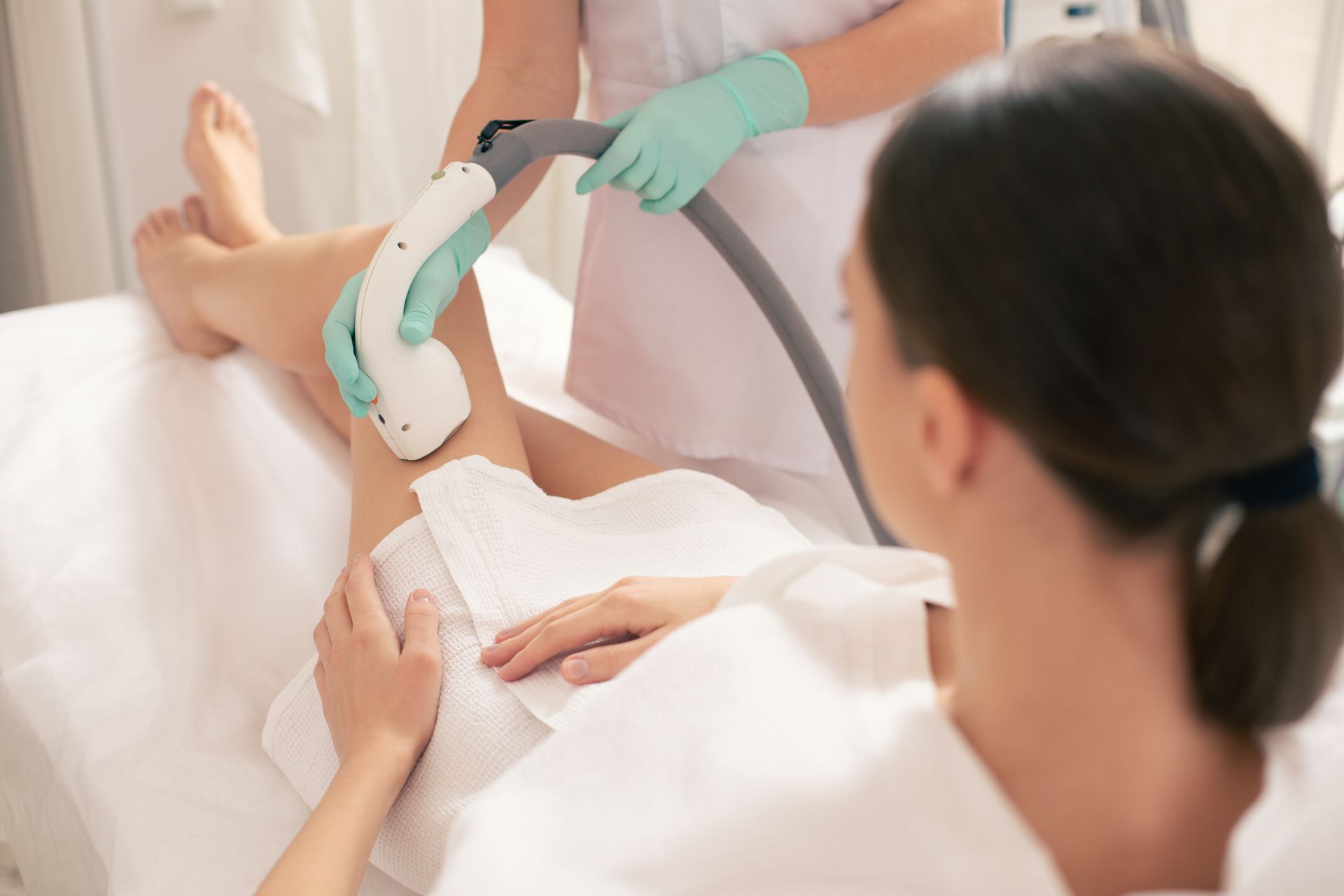 A woman is getting a laser hair removal treatment on her legs.