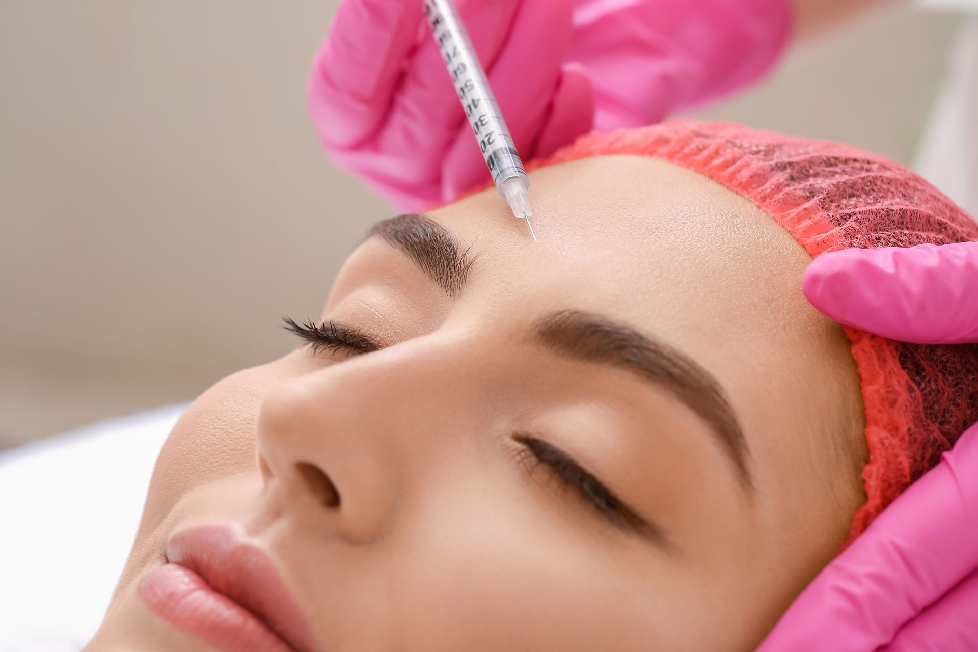 A woman is getting a botox injection in her forehead.