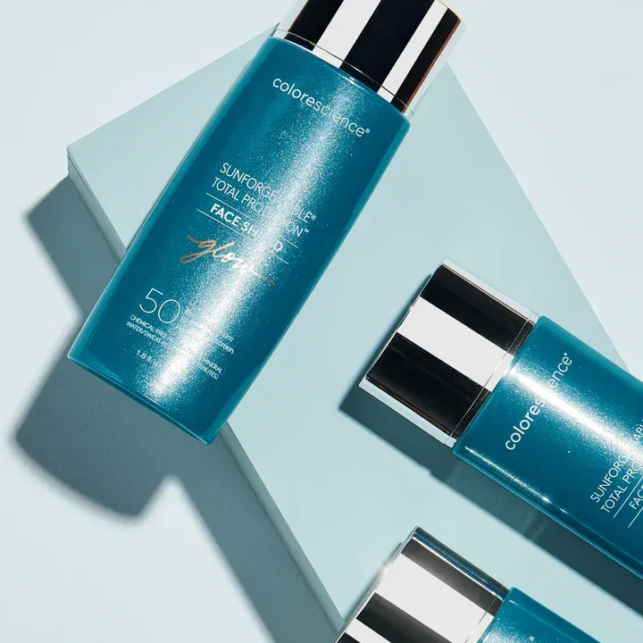 Three bottles of colorscience sunscreen are sitting on a blue surface.