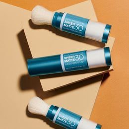 Three tubes of sheer matte 30 sunscreen are stacked on top of each other on a table.