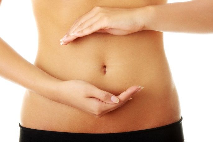 A woman is holding her hands on her stomach.