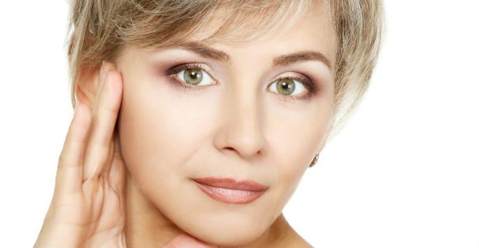 A close up of a woman 's face with her hand on her face.
