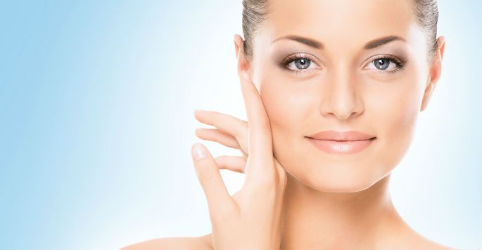 A woman is touching her face with her hand and smiling.
