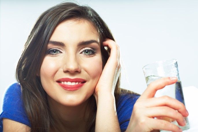 A woman is holding a glass of water in her hand.