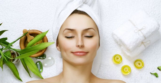 A woman with a towel wrapped around her head is laying on a massage table.