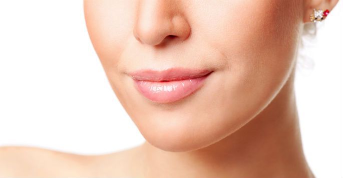 A close up of a woman 's face with earrings on a white background.