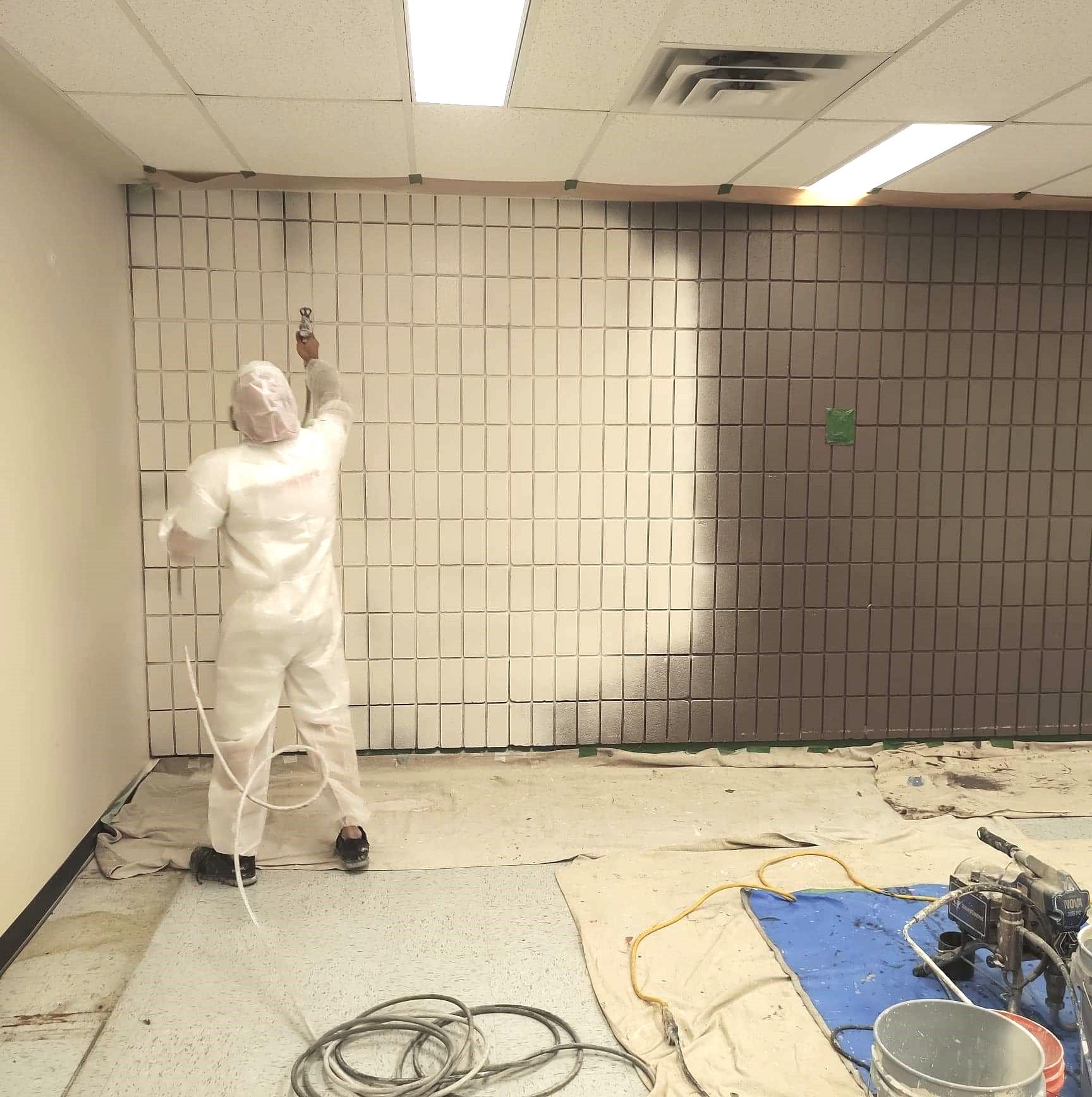 Un homme en costume blanc peint un mur