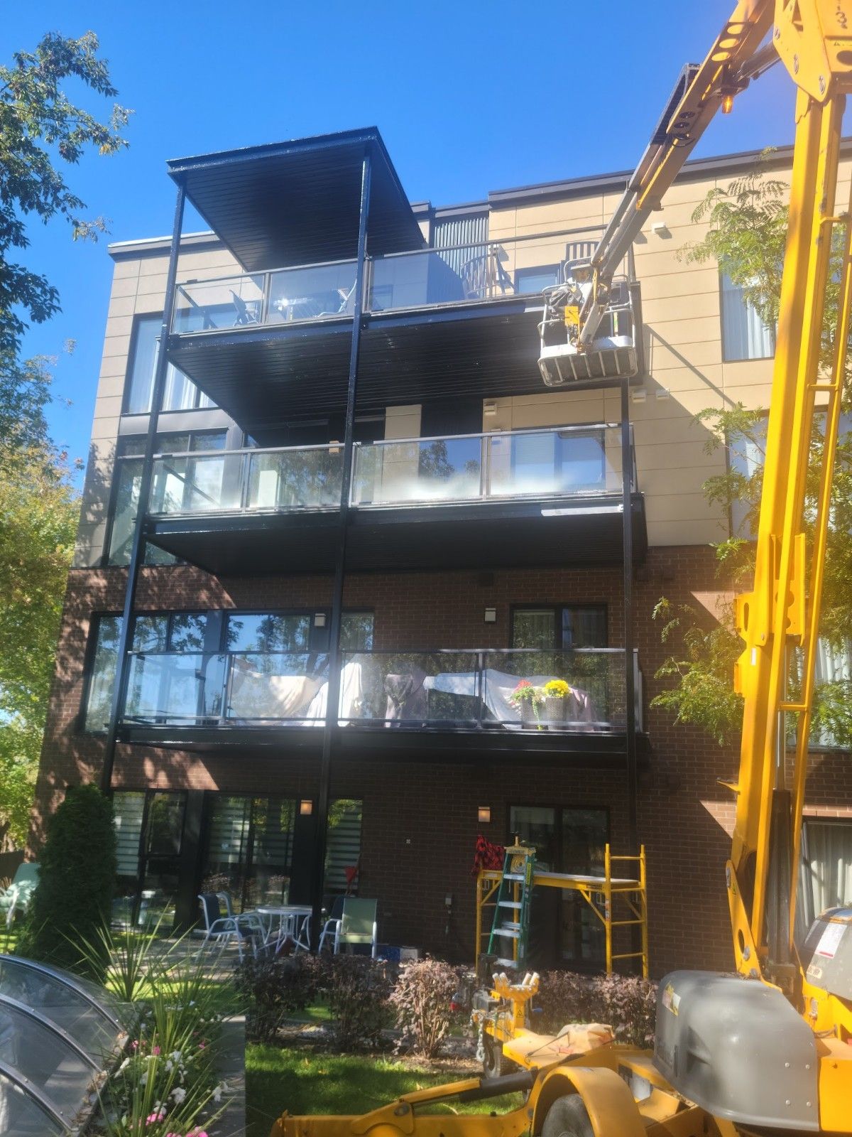 Une grue jaune travaille sur les balcons d'un immeuble