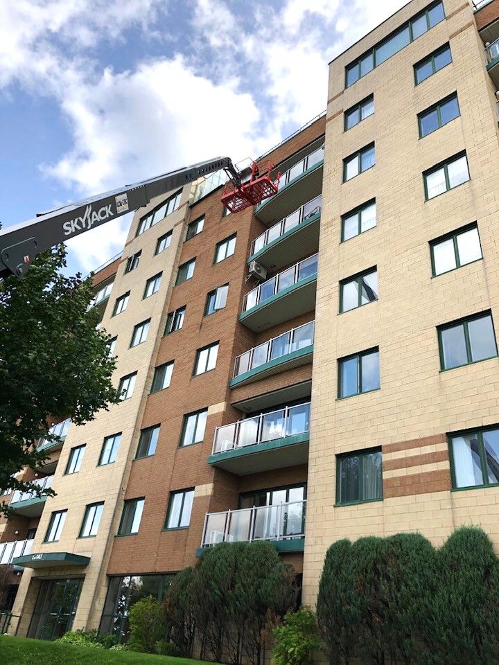 Peinture d'immeuble sur un grand bâtiment en brique surmonté d'une grue.