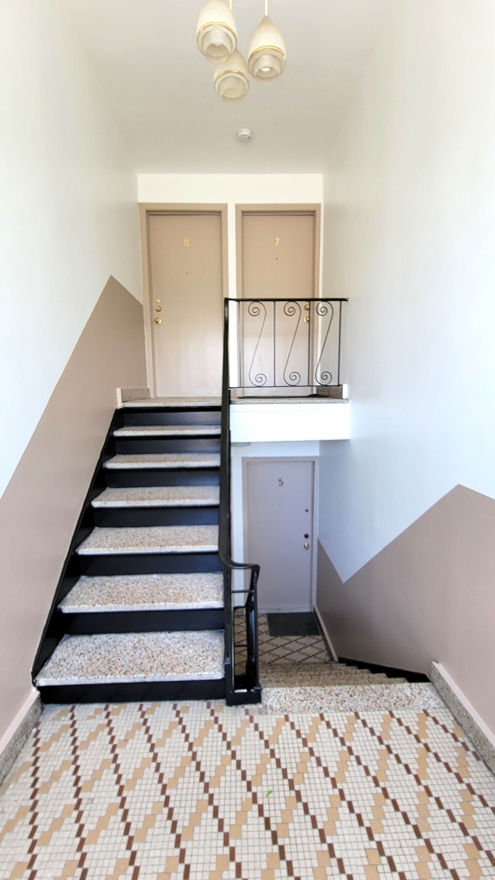 Un couloir avec des escaliers menant au deuxième étage d'un immeuble.