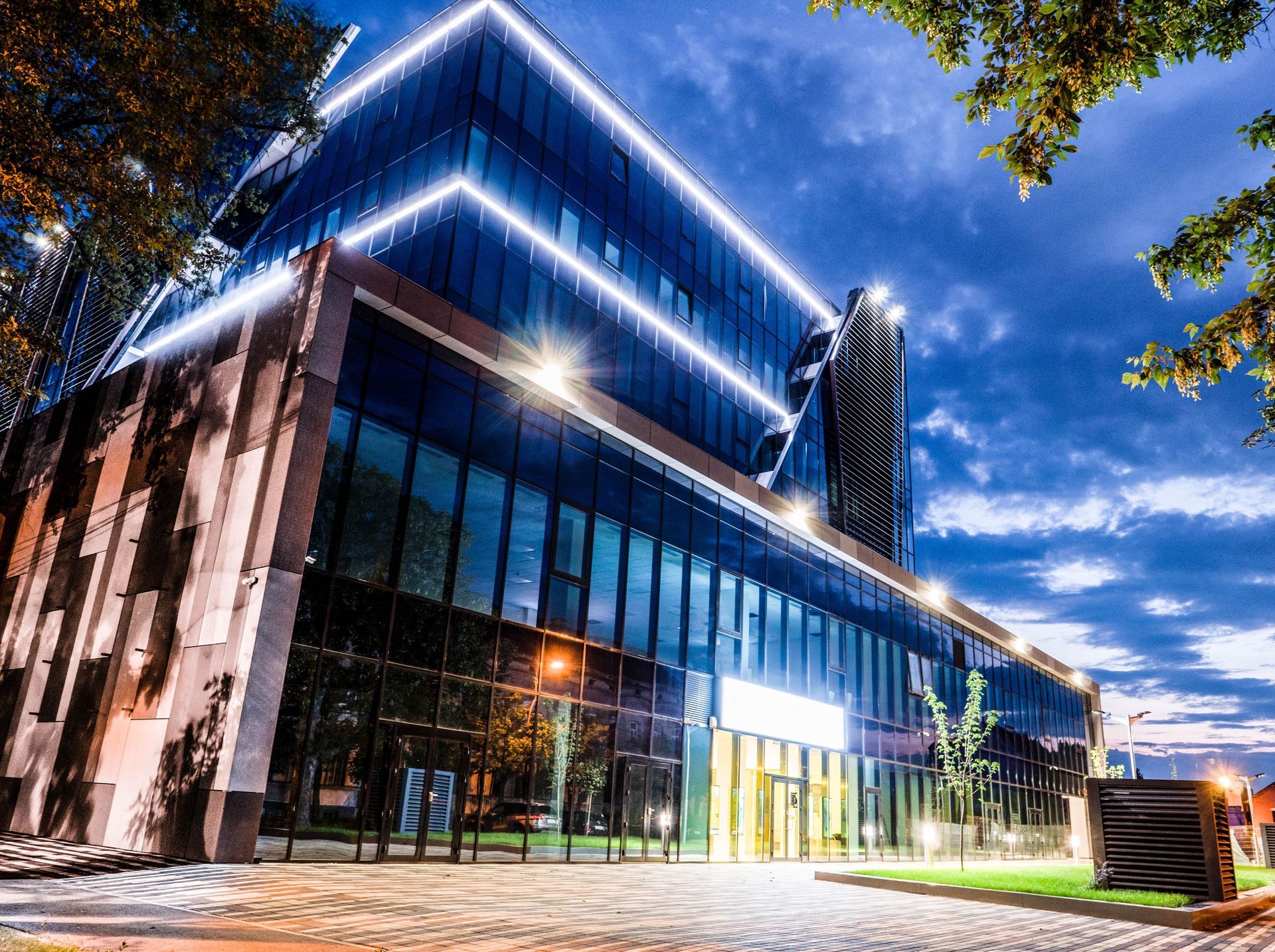 Modern glass office building lit with blue accent lights at dusk