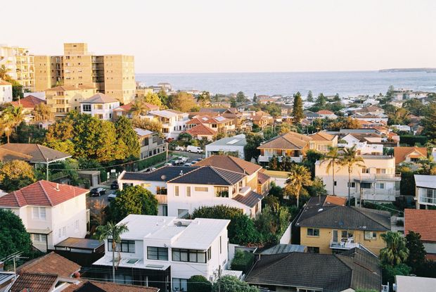 Coastal hillside neighborhood with houses, palm trees, and the ocean in the background