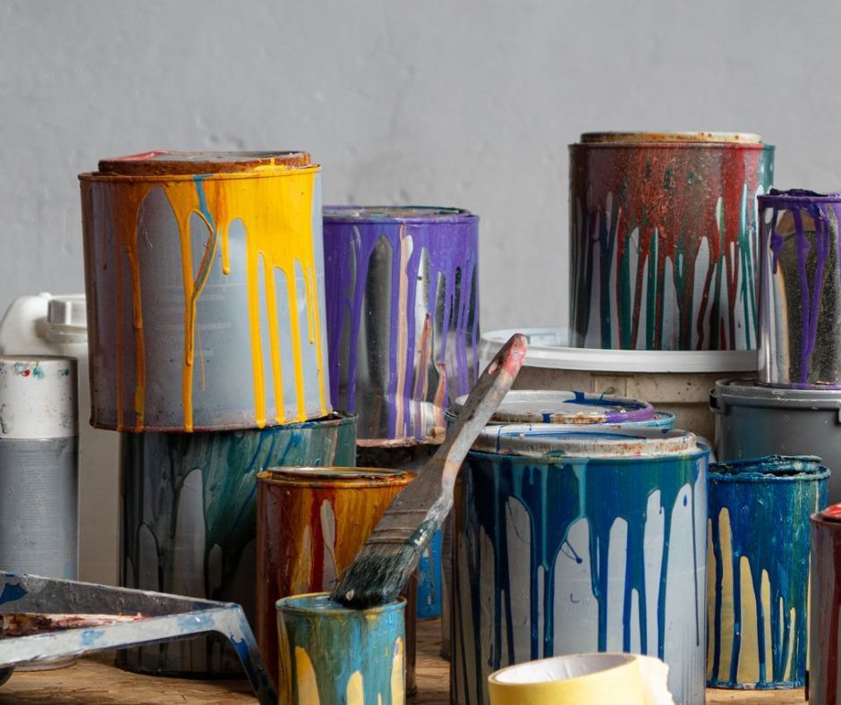 Un tas de pots de peinture sont empilés les uns sur les autres sur une table.