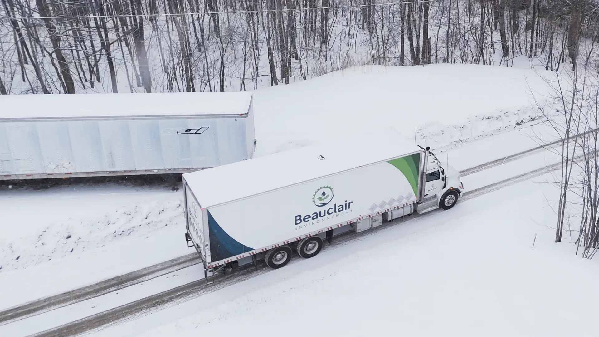 Un semi-remorque roule sur une route couverte de neige.