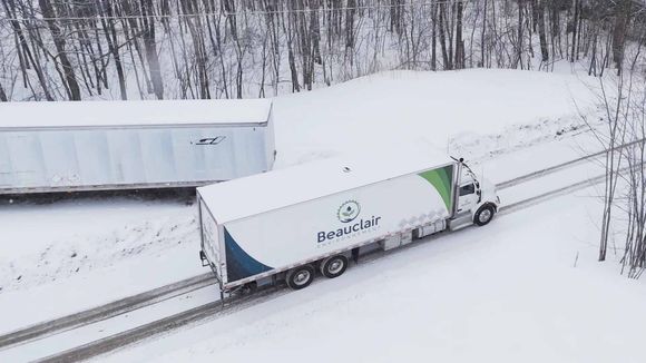 Un semi-remorque roule sur une route couverte de neige.