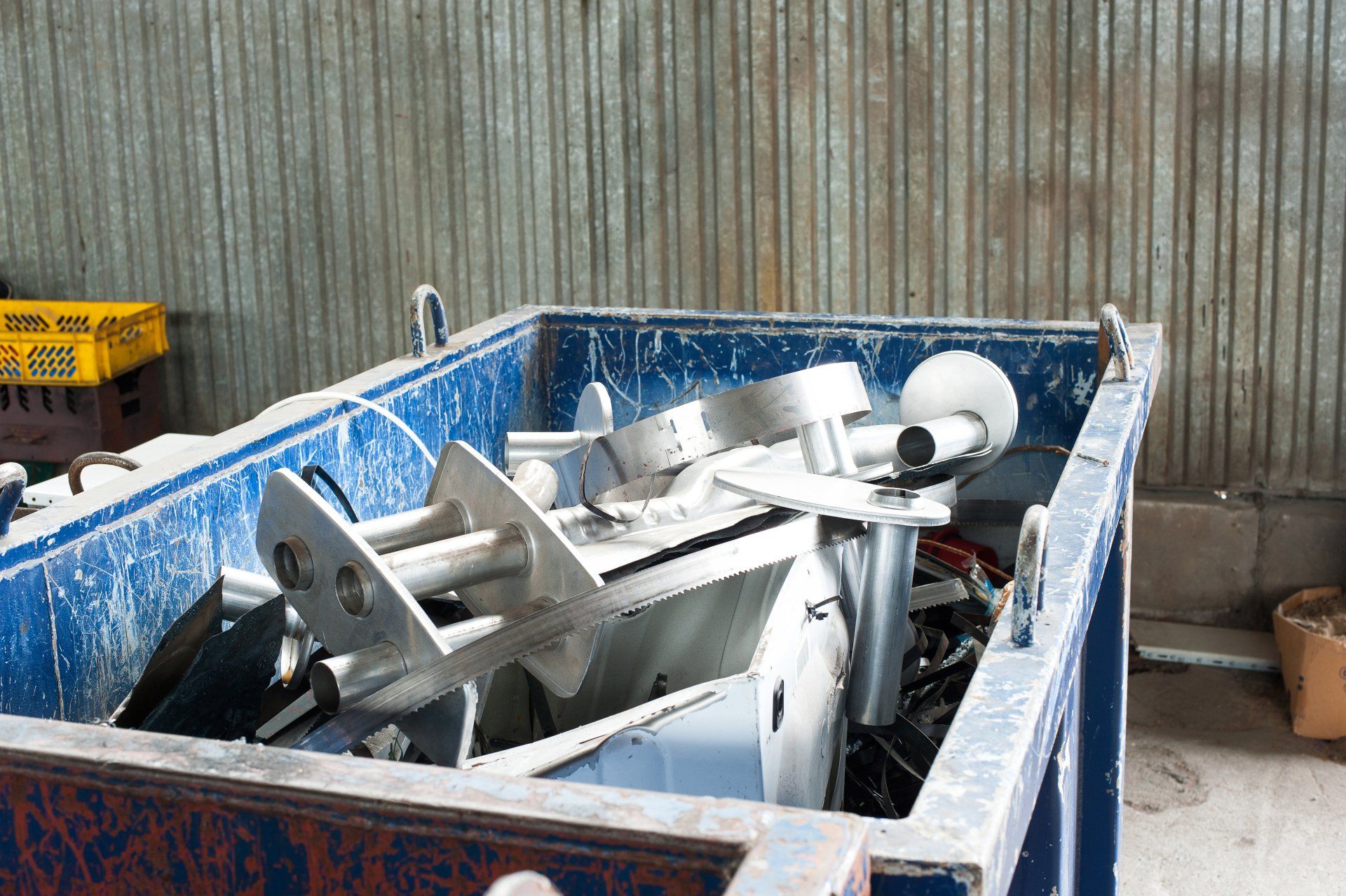 Une benne bleue remplie de déchets métalliques.