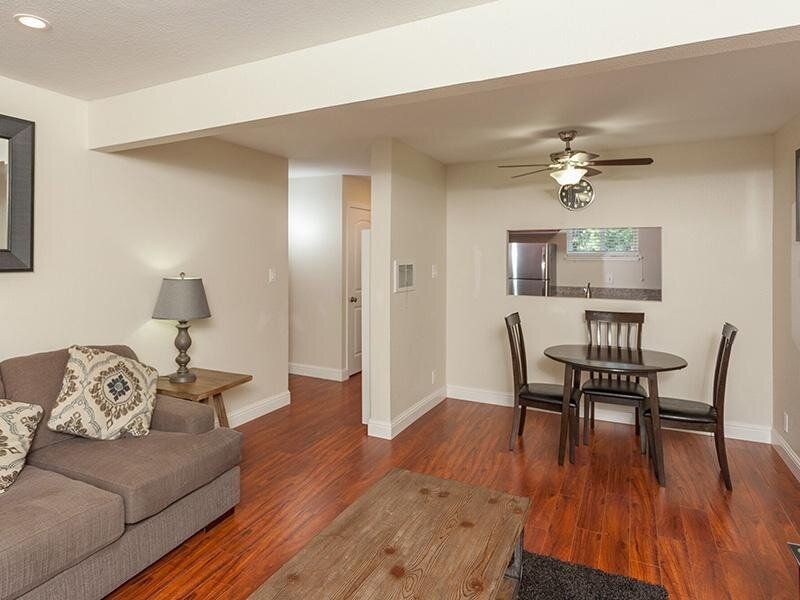 Living room with sofa, coffee table, and round dining table near an open kitchen pass-through.
