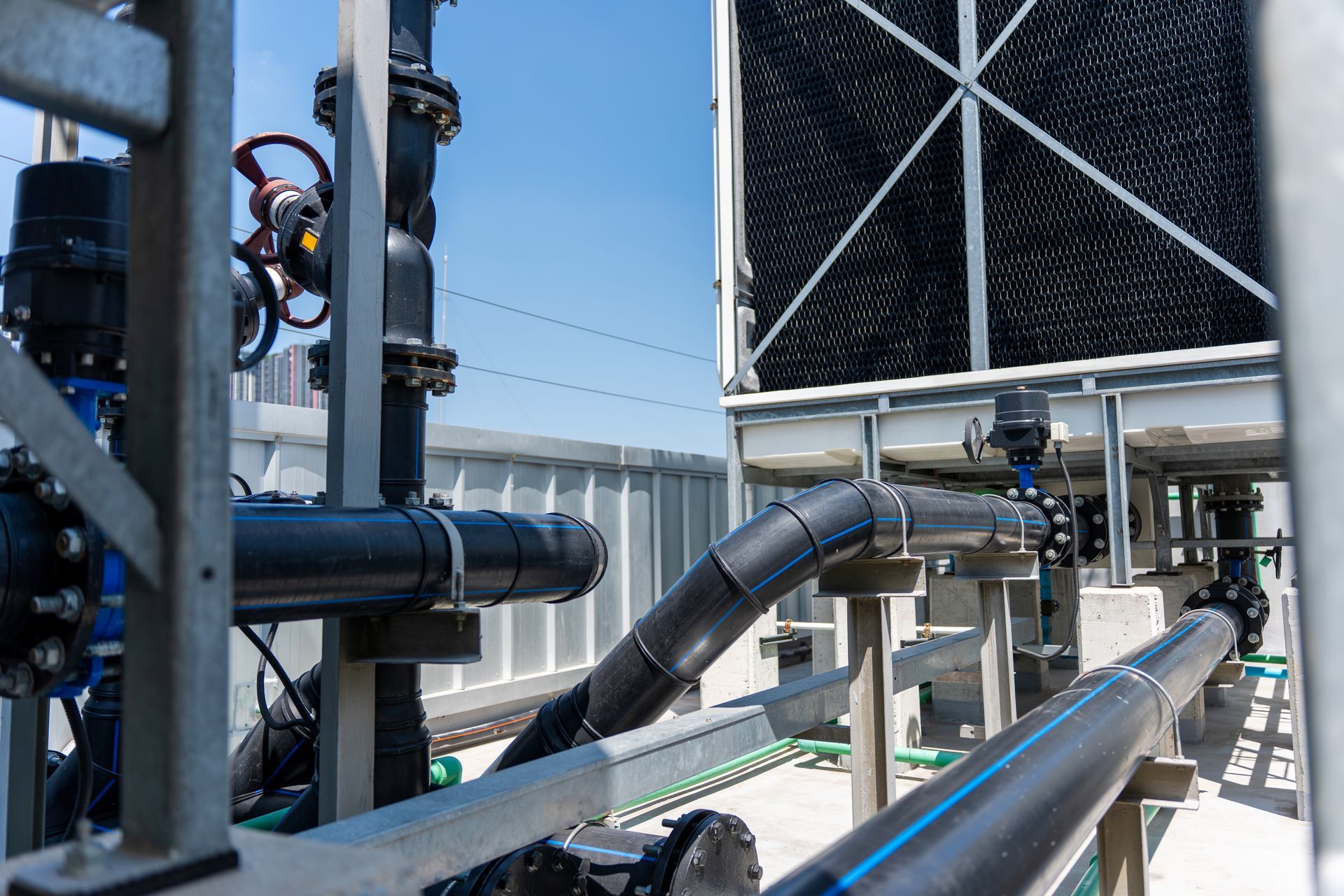Industrial piping and cooling unit with black insulated ducts under a blue sky