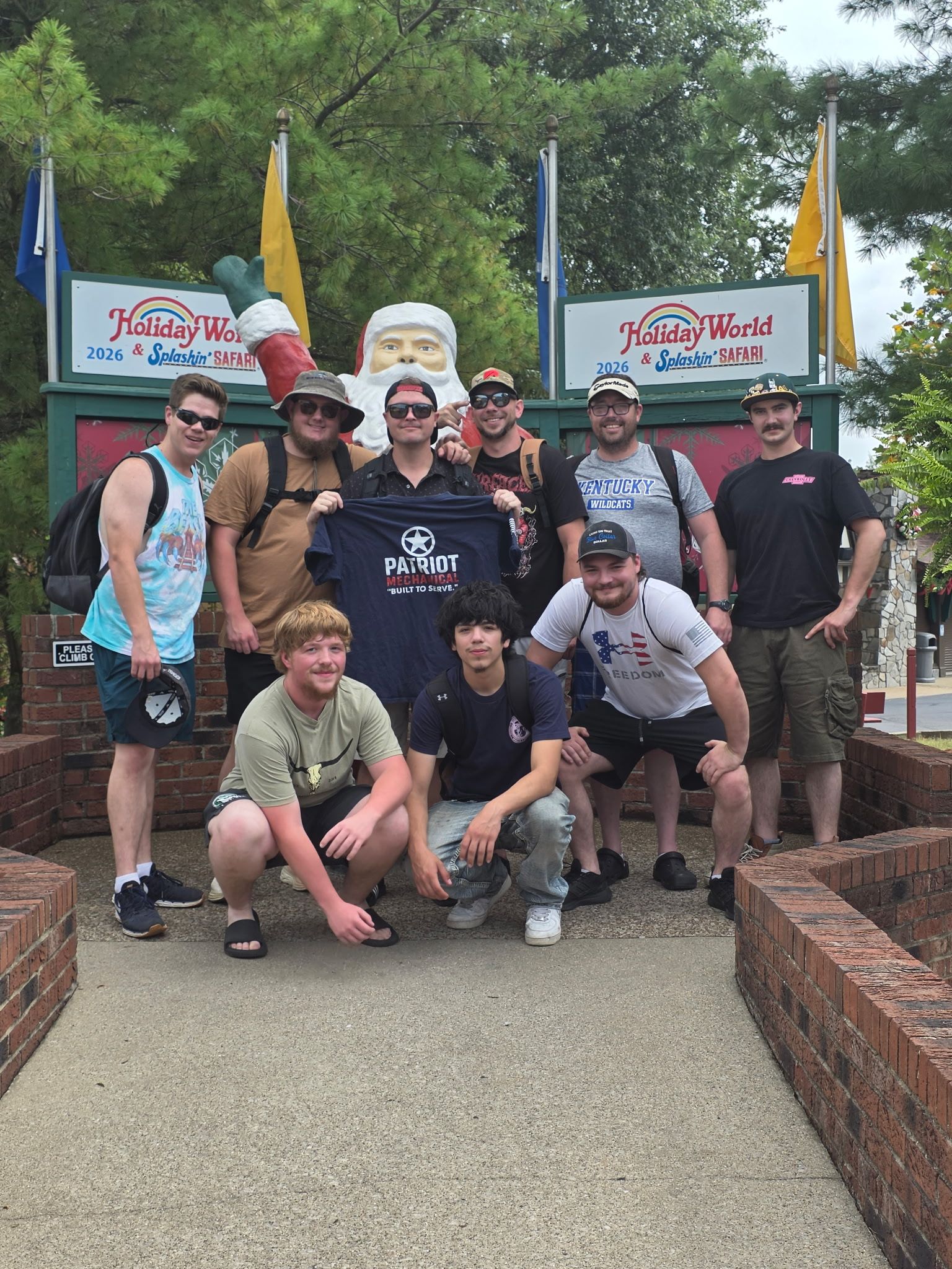 Group posing outdoors at a trailhead, with banners and flags behind them. Group posing outdoors at a trailhead, with banners and flags behind them.