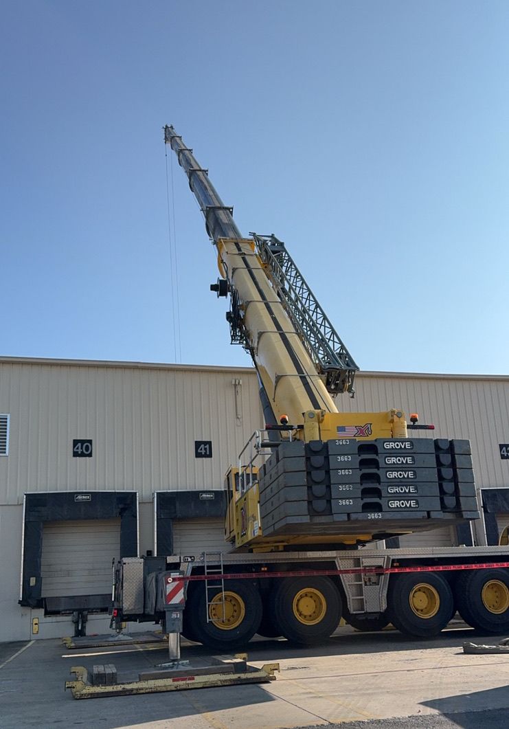 Crane truck with extended boom parked beside a warehouse loading dock