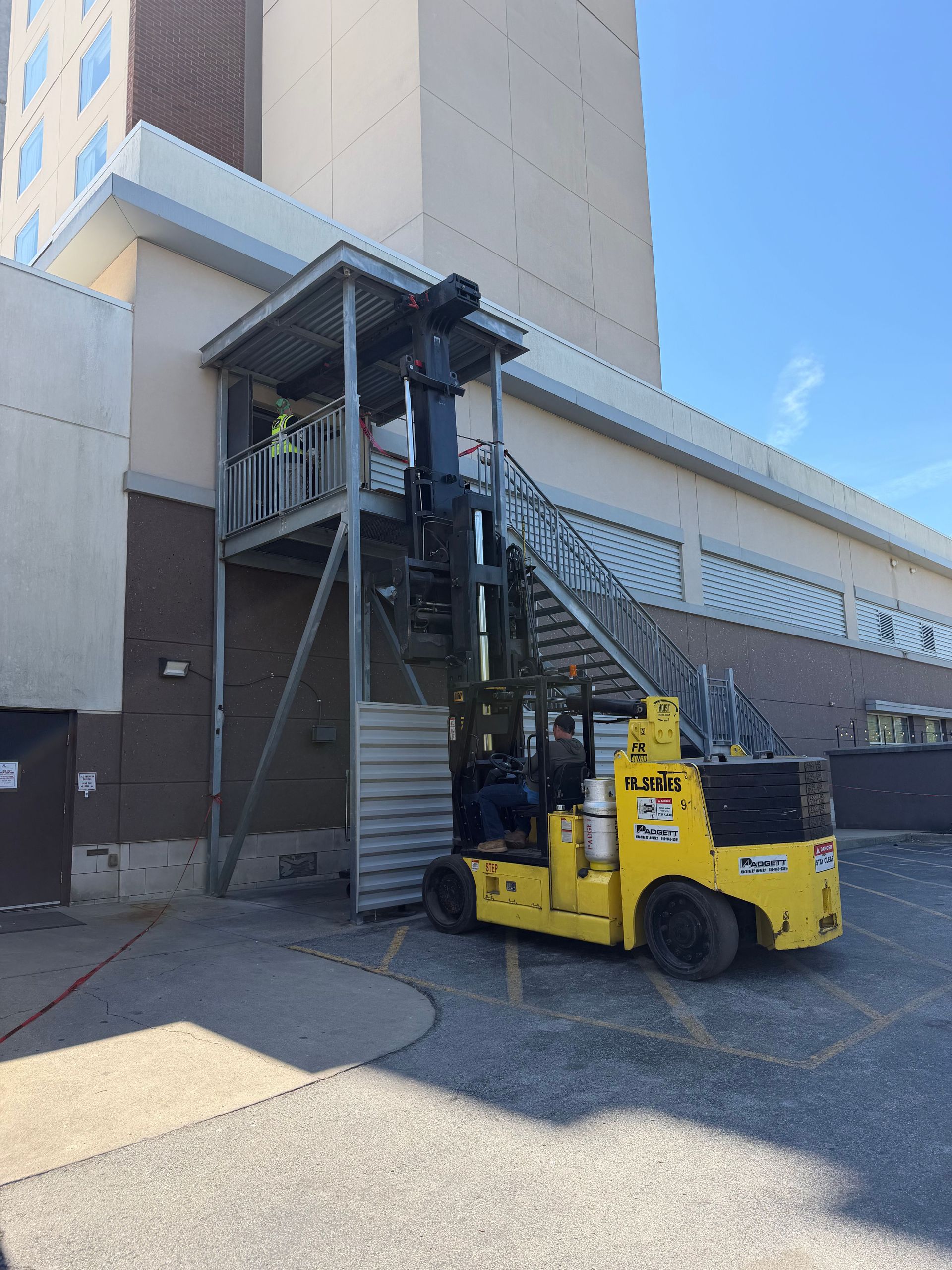 Forklift parked beside an outdoor metal stairway on a building loading dock