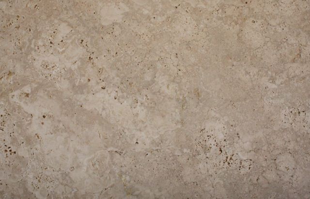Tan-colored travertine stone, with a mottled surface and small holes.
