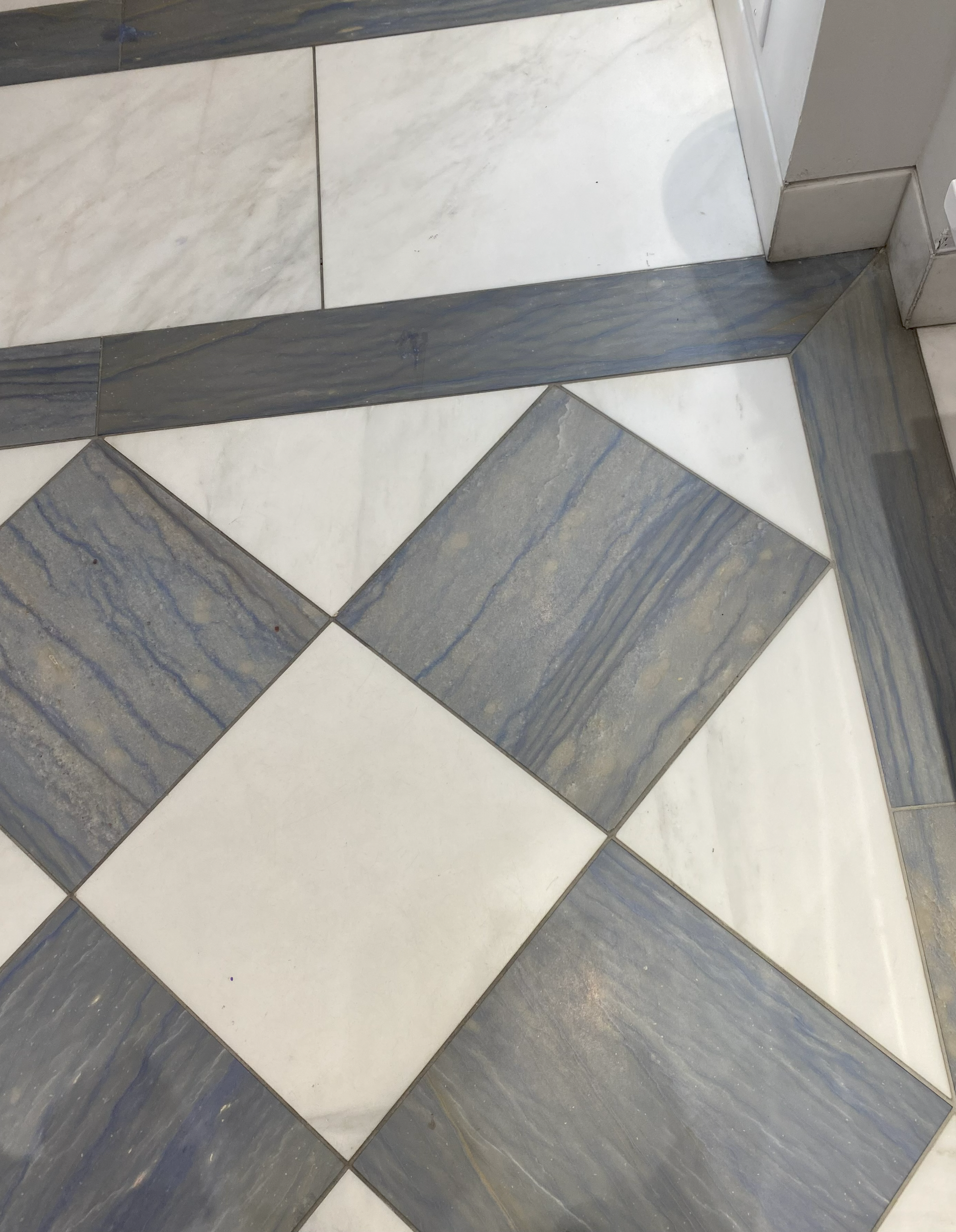 Floor with alternating blue and white marble tiles in a diamond pattern, outlined in gray.