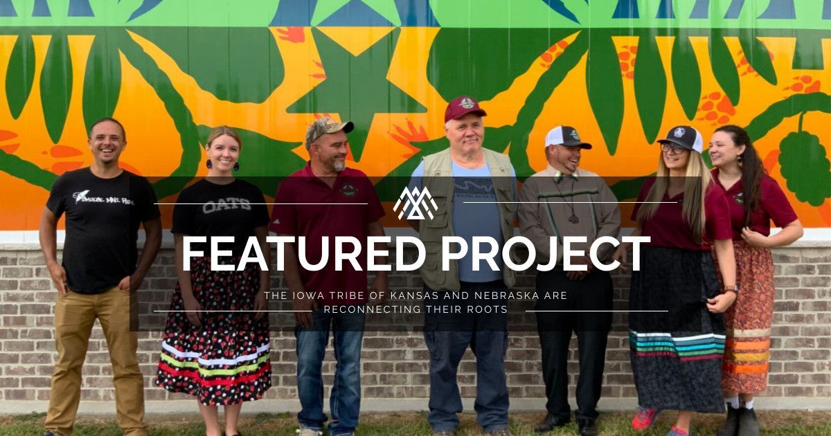 A group of people are standing in front of a brick wall.