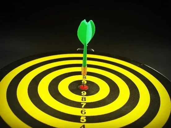 black and yellow target with green dart in bullseye