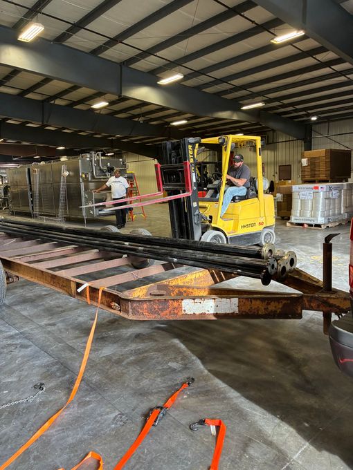 A welding trailer parked next to a building with cables and hoses on the ground.