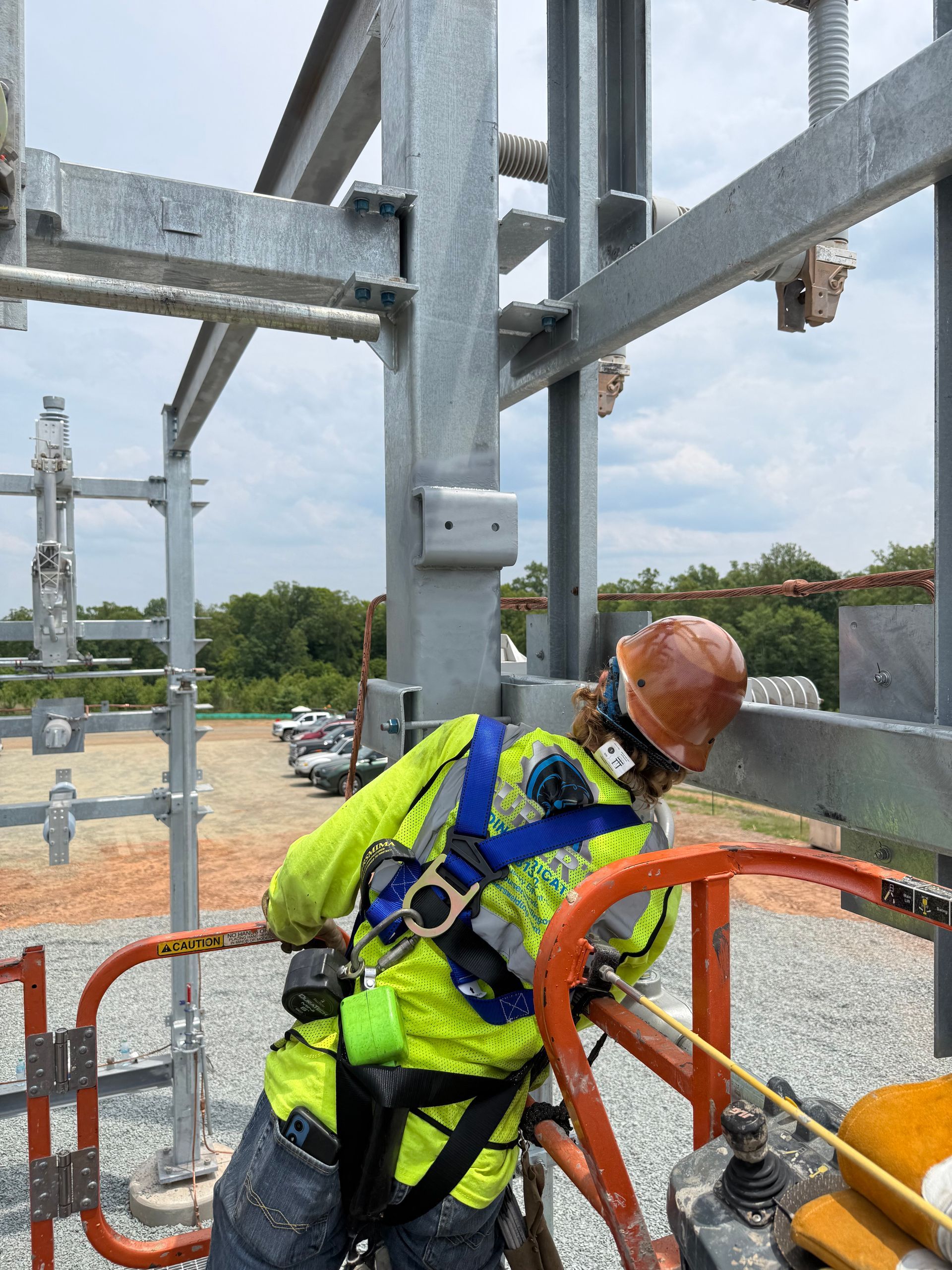Worker in neon safety gear and hard hat leaning on orange railing at an outdoor steel construction site