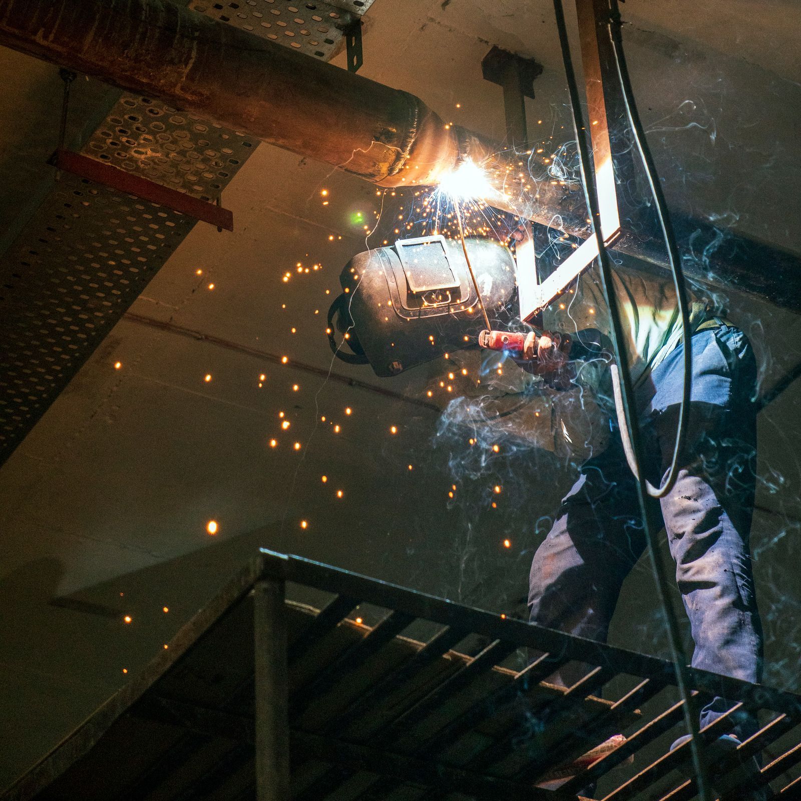 Welder using a torch, creating sparks on metal.