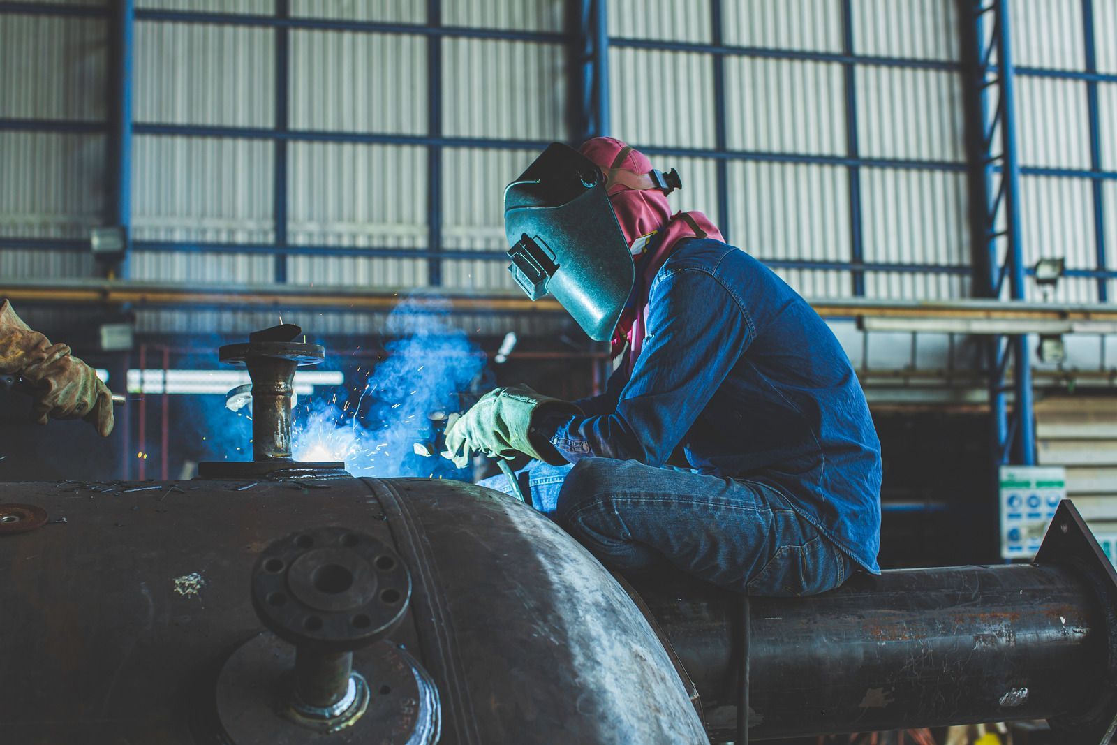 Welder using a torch, creating sparks on metal.