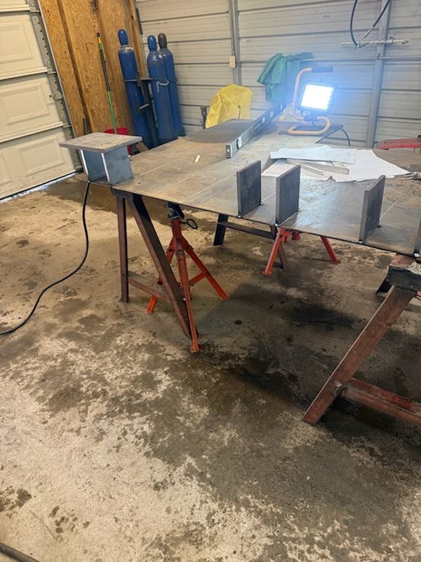 Welding setup with metal pieces on a work table, lit by a bright welding light, inside a workshop.