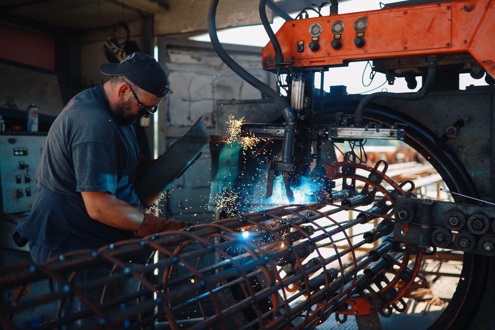Welder using a torch, creating sparks on metal.