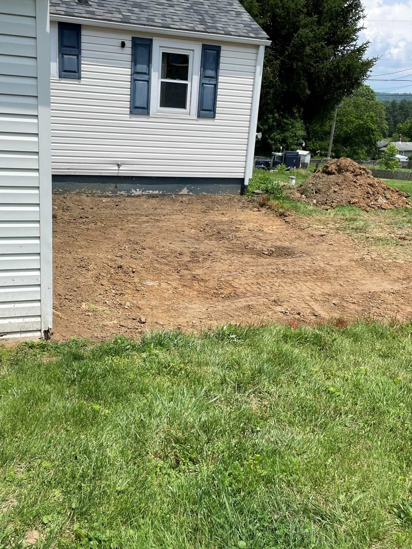 Side of a house with fresh dirt landscaping and grass in the foreground