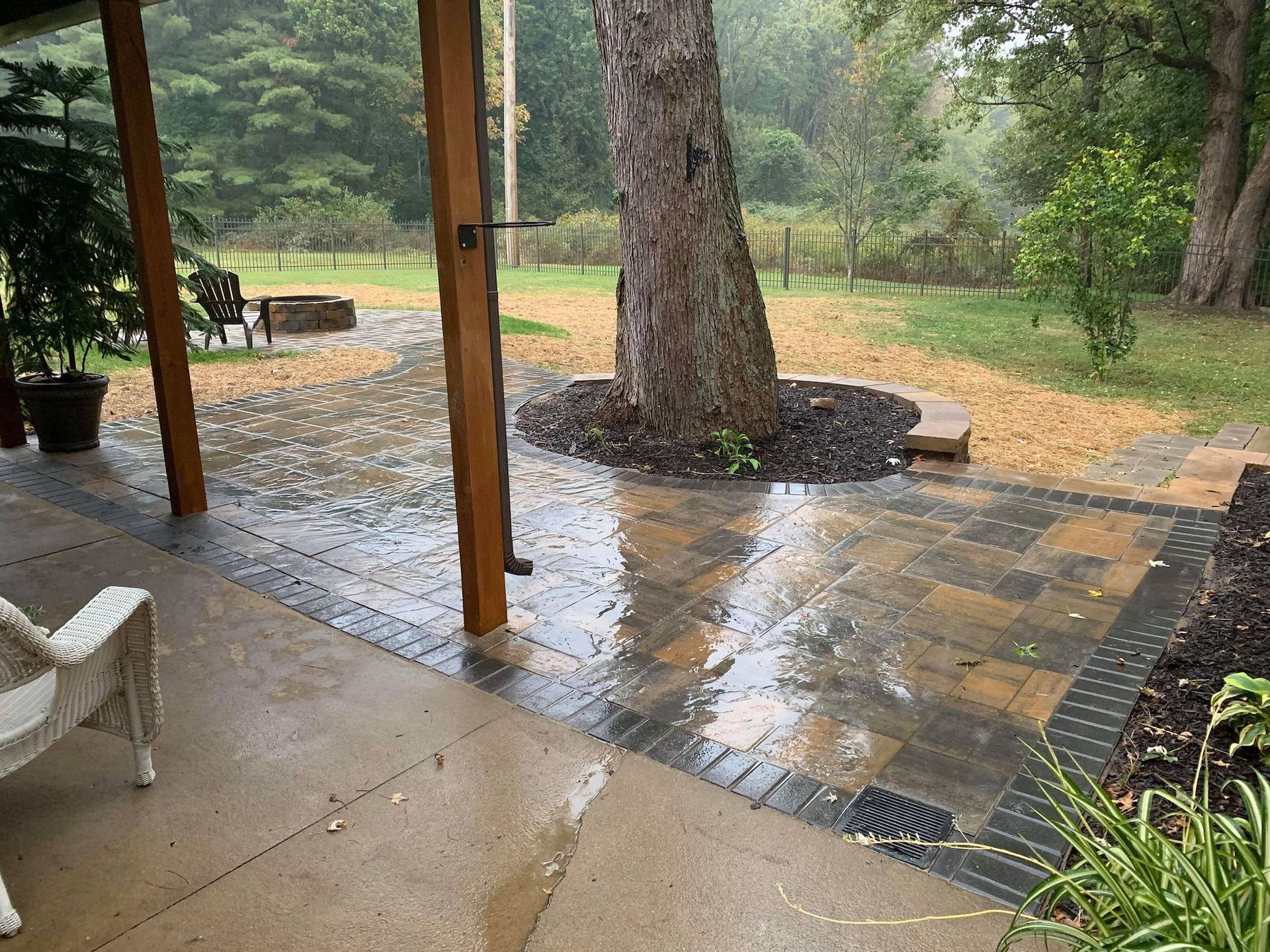A patio with a tree in the middle of it on a rainy day.