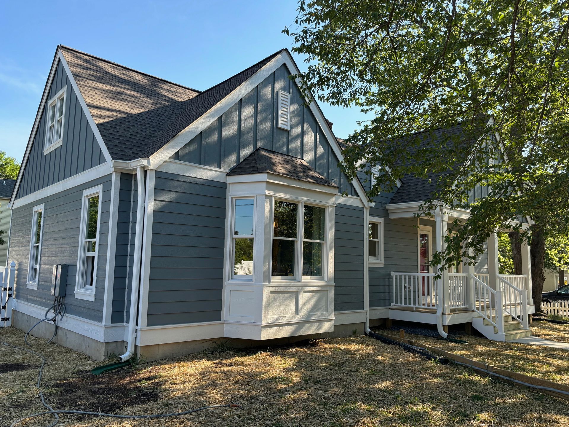 A house with a porch and a tree in front of it