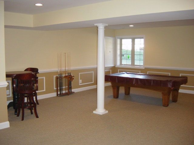 A basement with a pool table and chairs