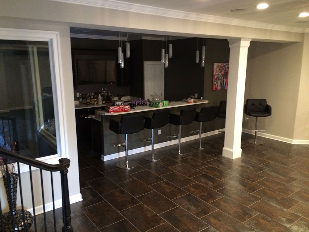 A basement with a bar and chairs in it