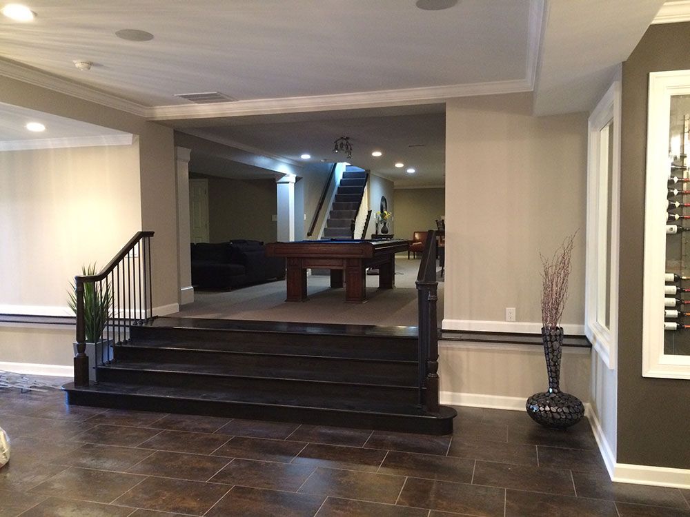 A basement with a pool table and stairs leading up to it.