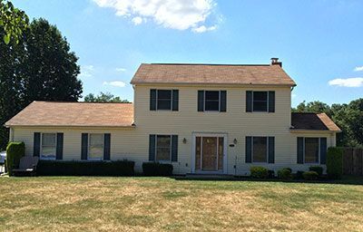 A large house with a brown roof and black shutters