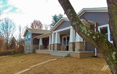 A house with a porch and a tree in front of it